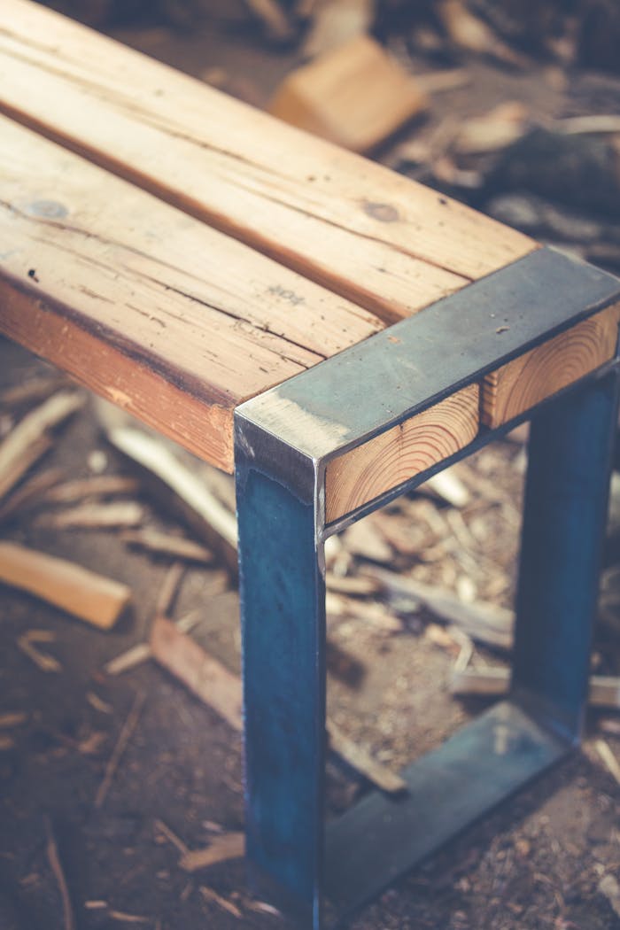 about-01 A rustic wooden bench with a metal frame on a textured surface, ideal for outdoor decor.