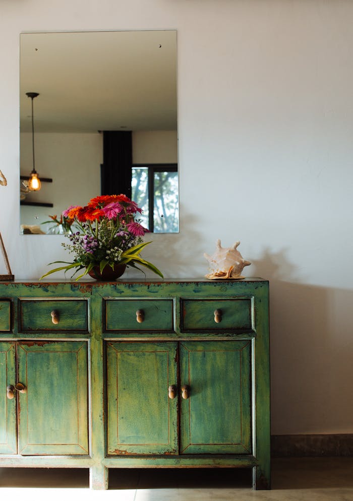 our-services-1 Stylish room with a vintage green cabinet, flower vase, and decorative shell.